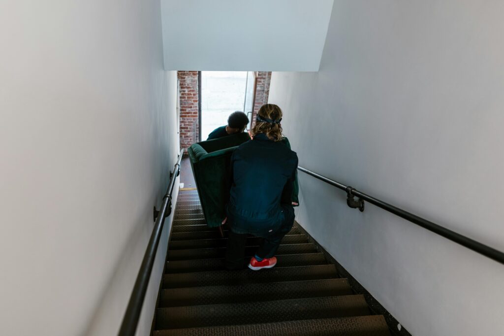 Two professional movers carrying a sofa down the stairs