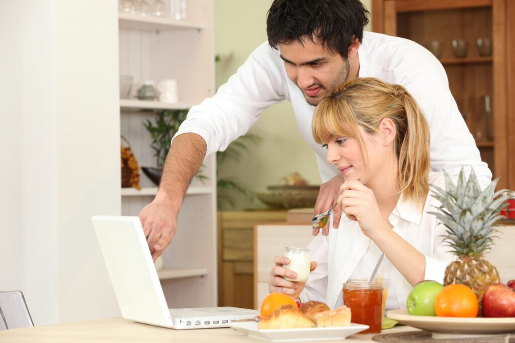 A couple comparing removals cost through a laptop while having breakfast