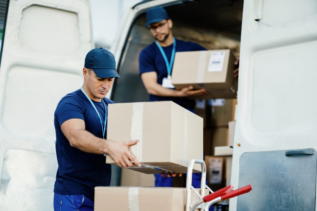 Busy man and van crew carrying moving boxes from the van