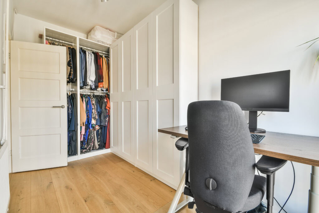 Small room with desk, chair, computer, and closet